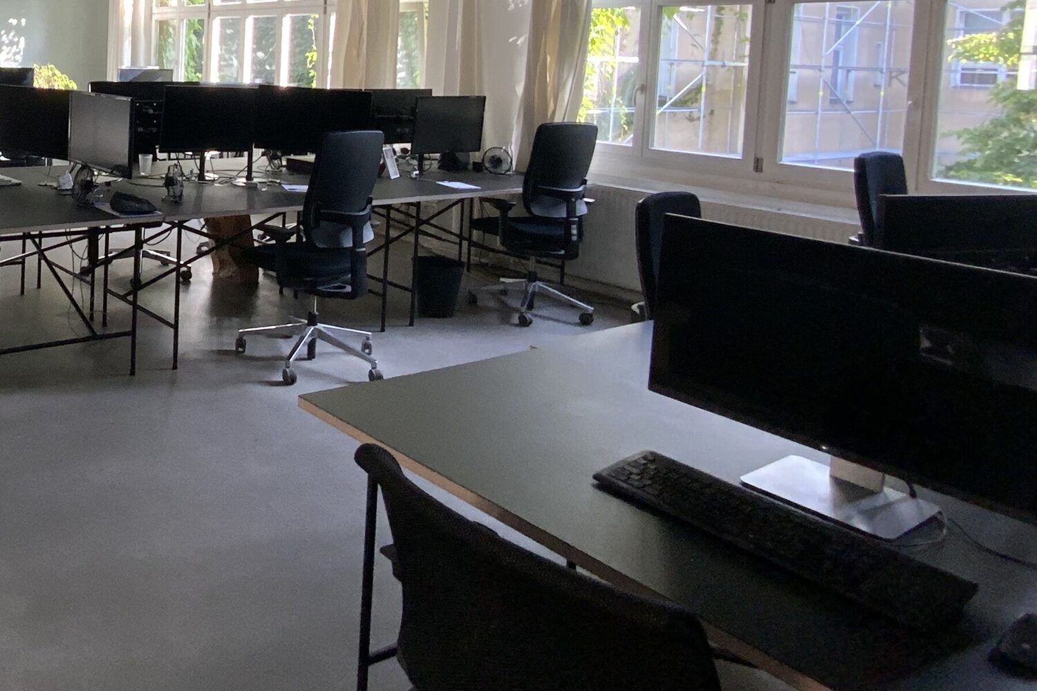 An office with desks, screens and chairs