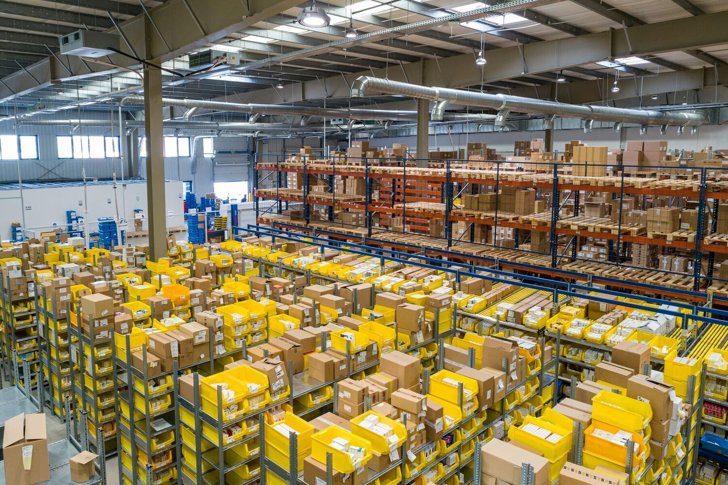 A warehouse with shelves, boxes and yellow bins